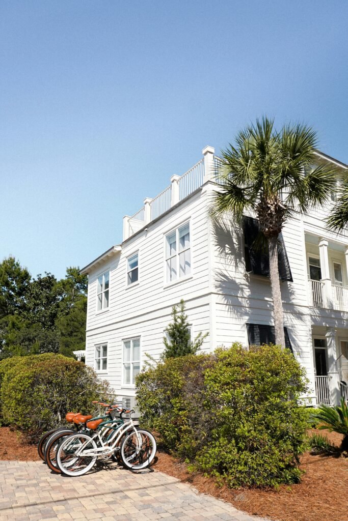 White coastal house with bicycles and palm tree under blue sky, perfect for real estate and travel imagery.